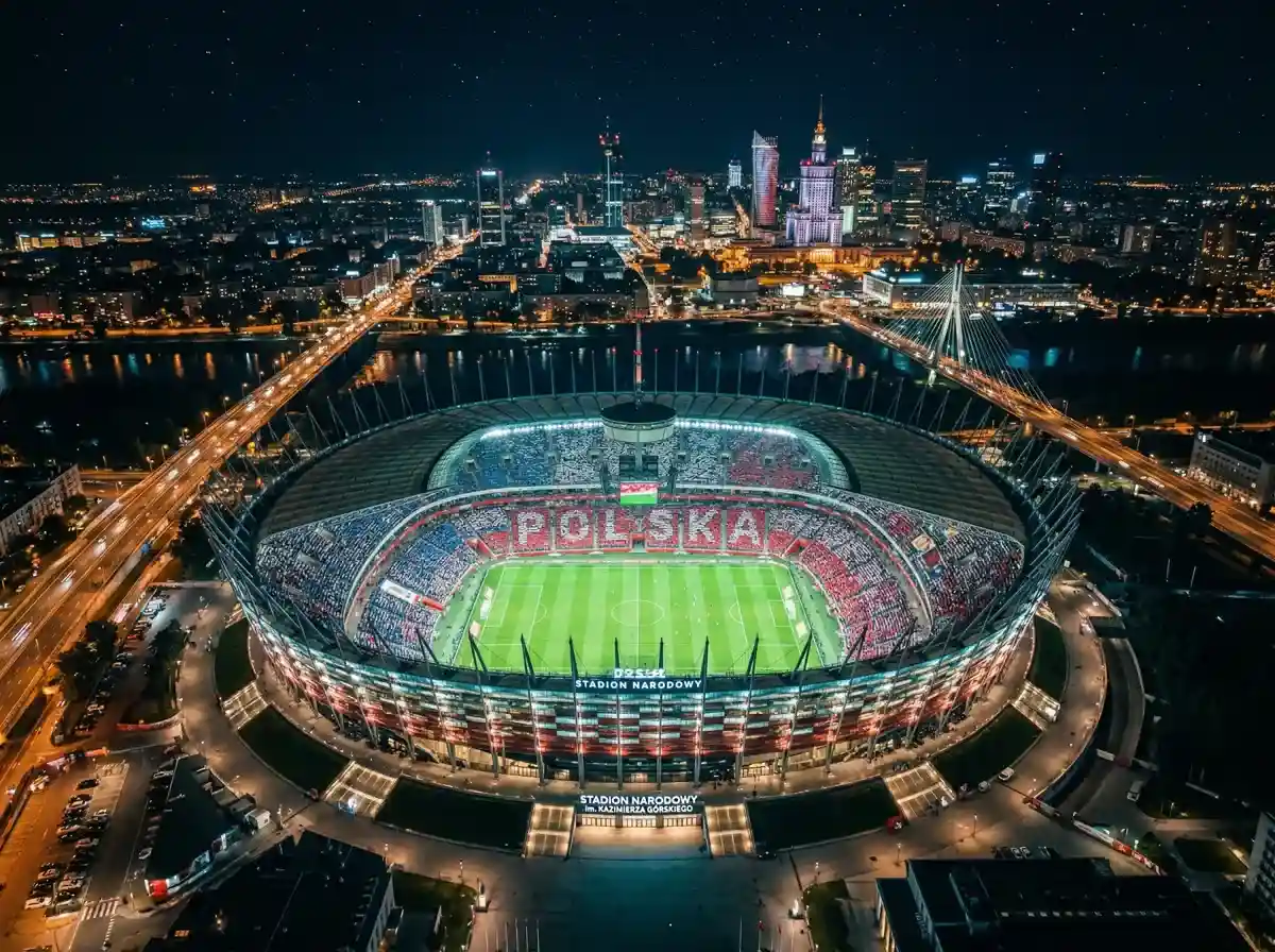 Nowoczesny stadion piłkarski z zieloną murawą i pełnymi trybunami podczas meczu wieczornego